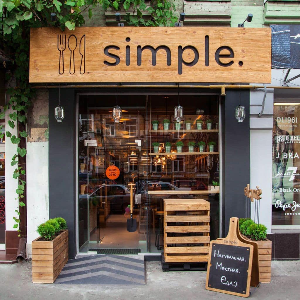 Slate grey shop front with arched windows and big glass windows on a paved street